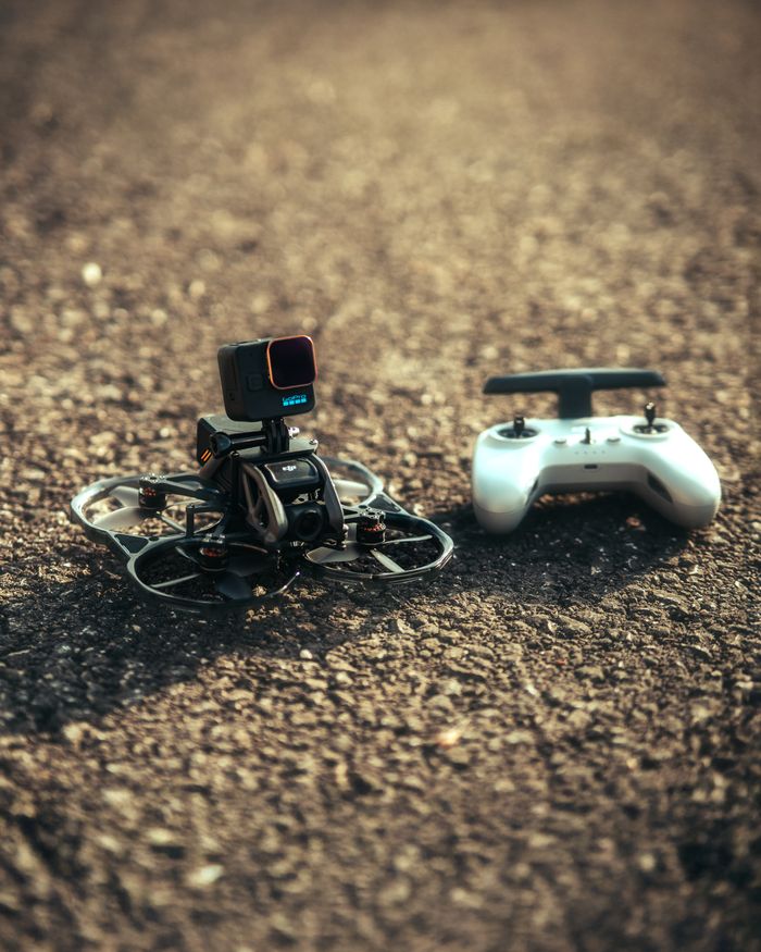 Close-up of a compact drone with a camera and controller on an asphalt surface, ideal for tech and travel imagery.